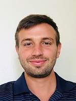 Man wearing blue polo with short hair parted to the right smiling at camera